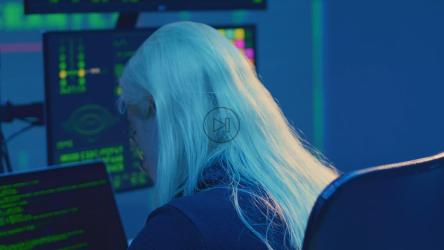 一名年轻的黑客出现在各种屏幕前，屏幕上显示着技术和安全信息。[免费商用]