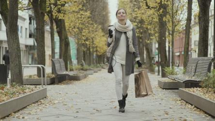 快乐的女人在秋天拿着购物袋散步[]