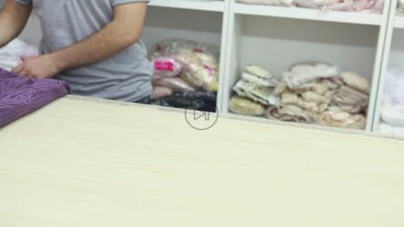 工人在桌子上测量织物[]