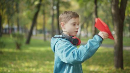 小男孩在公园玩纸飞机[]