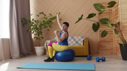 男子坐在健身球上以讽刺的方式举起哑铃[]