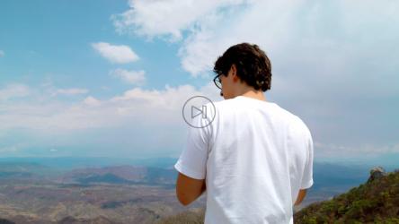 一位年轻的摄影师在山顶用专业相机拍照[免费商用]