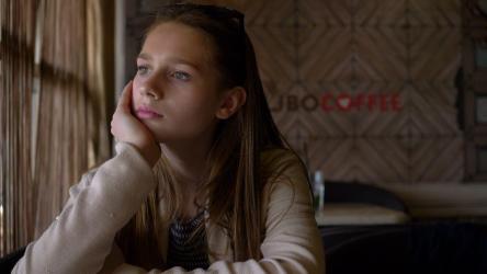 年轻女孩坐在咖啡店里看起来很担心[]