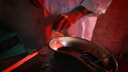 穿着实验服的男子戴上乳胶手套血腥 Gore:在血迹斑斑的房间里，一个穿着实验服的恐怖男子戴上了手套。