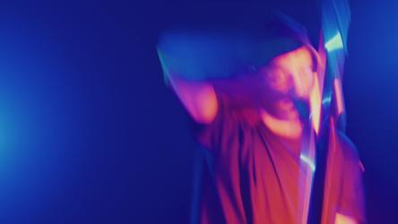 手里拿着光棍跳舞的舞者跳舞 Dance:年轻的舞者在蓝色的派对灯光下，用手转动着一根光棒跳舞。