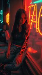 一位年轻的纹身女子坐在一扇有红色霓虹灯标志的窗户旁，护理着她的头发AI生成 AI Generated:在灯光昏暗的环境中，一位身上有复杂纹身的年轻女子安静而孤独地坐在一家靠窗的咖啡馆旁，在那里，一个充满活力的红色霓虹灯标志的环境光在整个场景中投射出温暖的深红色。