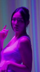 一位年轻舞者丰富多彩表演的垂直视频时尚 Fashion:在一段垂直视频中，一名身着粉红色灯光的舞者在彩色背景前表演。