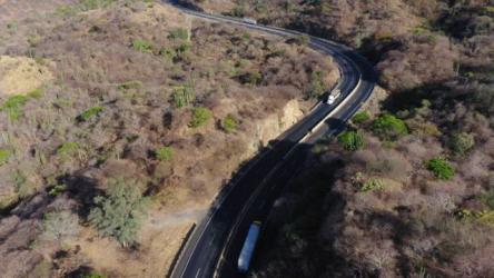 运输卡车在干旱植被中的黑色沥青路上滑行更多 More:运输卡车沿着一条黑色的柏油路平稳地滑行,这条路穿过一片广阔的干旱植被。黑暗的路面和干燥的植被之间的对比突显了地形崎岖、荒凉的美丽。